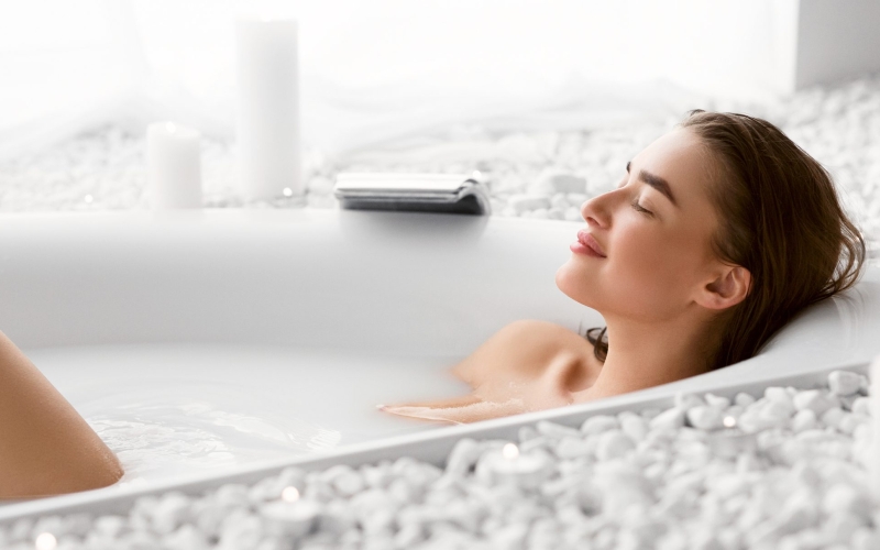 woman looking happy in a soaked in a bathtub by Studium Dekor.